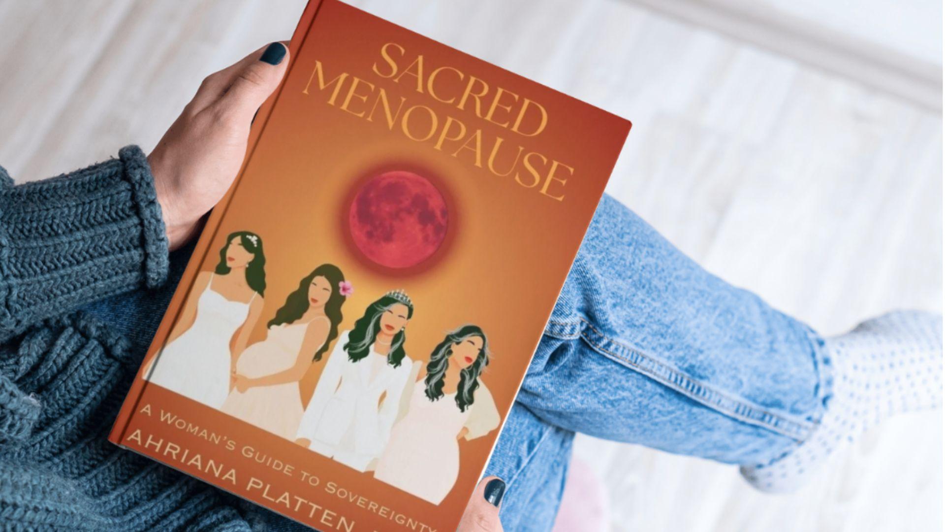 Person holding the book "Sacred Menopause" featuring illustrations of women and a full moon