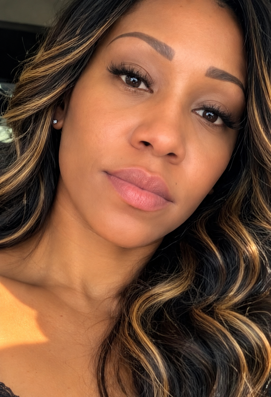 Close-up portrait of a woman with wavy hair and natural makeup.