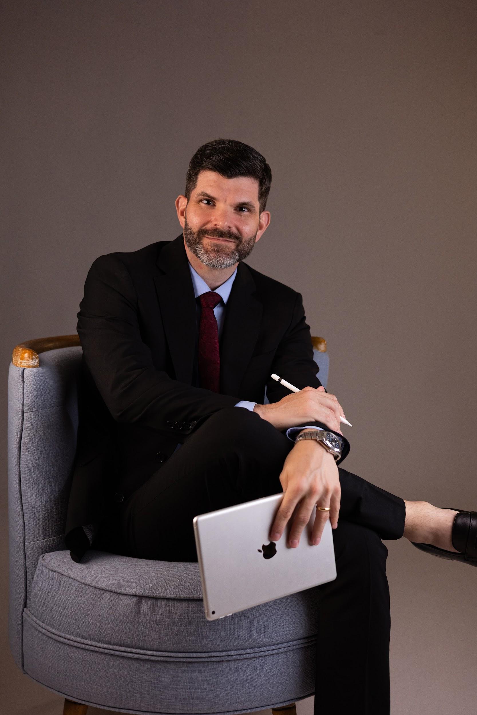 Professional man in a suit sitting on a chair, holding an iPad and pen