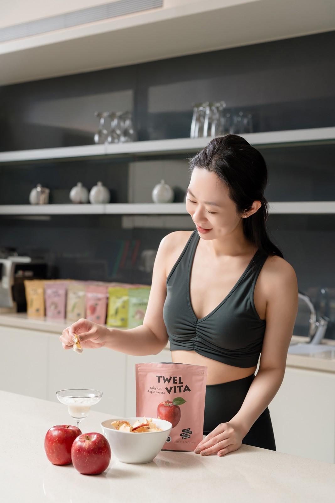Woman in activewear smiles while preparing a healthy snack in a modern kitchen