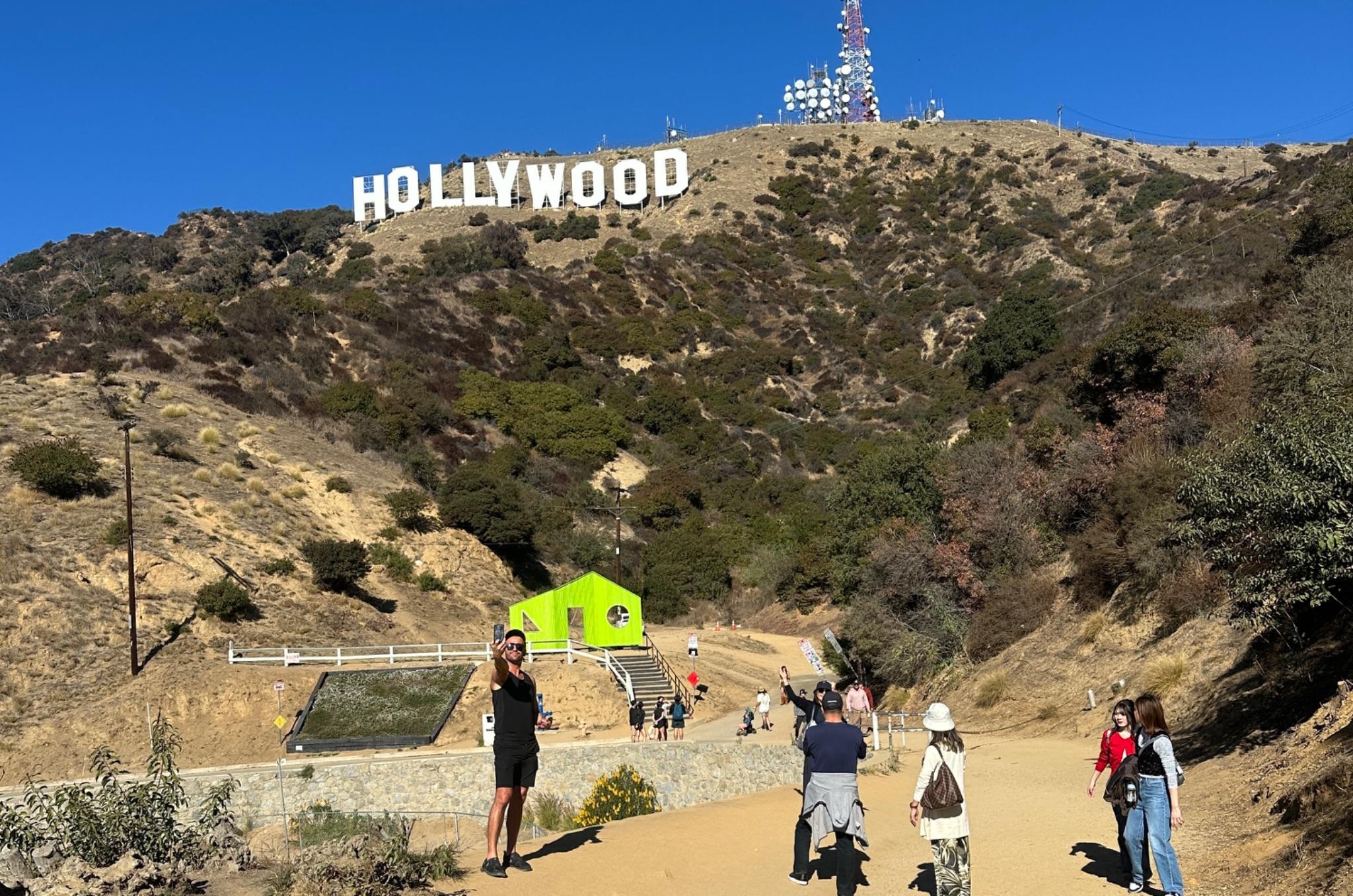 People walking on a path with the Hollywood sign in the background
