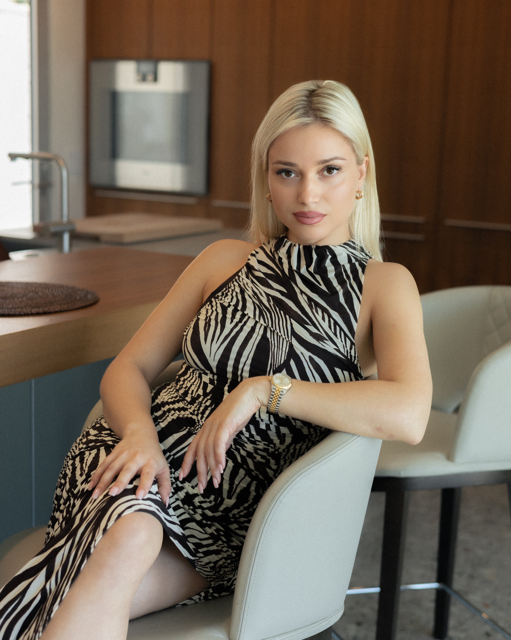 Woman in a zebra-patterned dress sitting in a modern kitchen setting