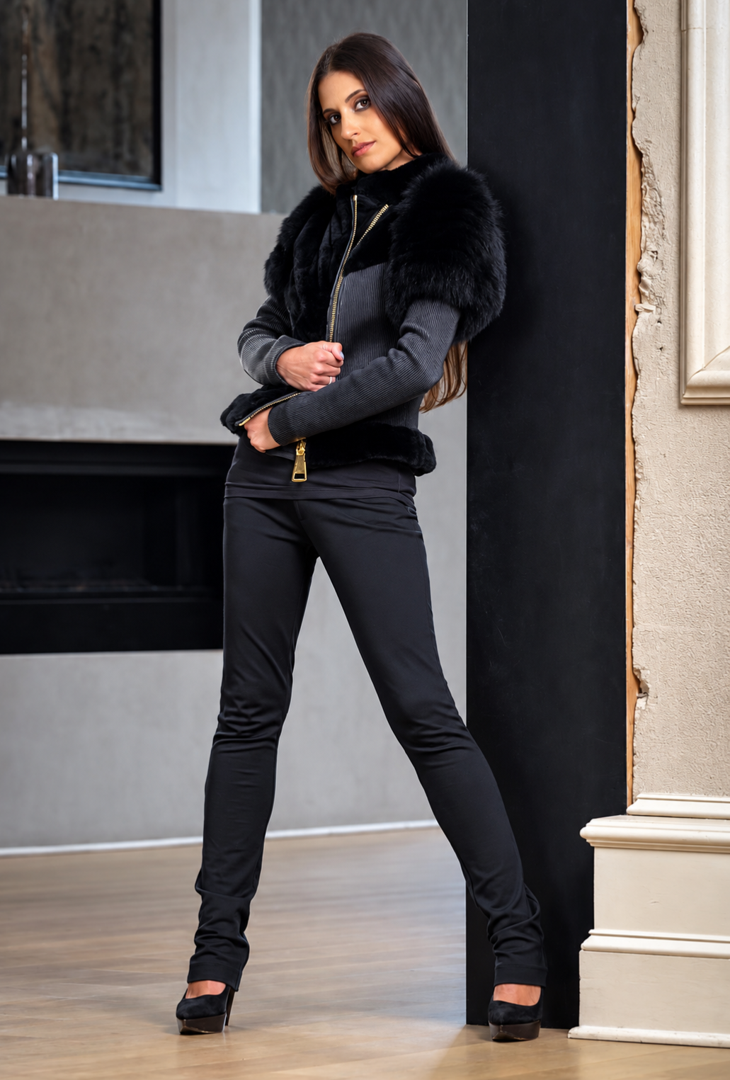 Woman in stylish black outfit with fur accents posing elegantly indoors
