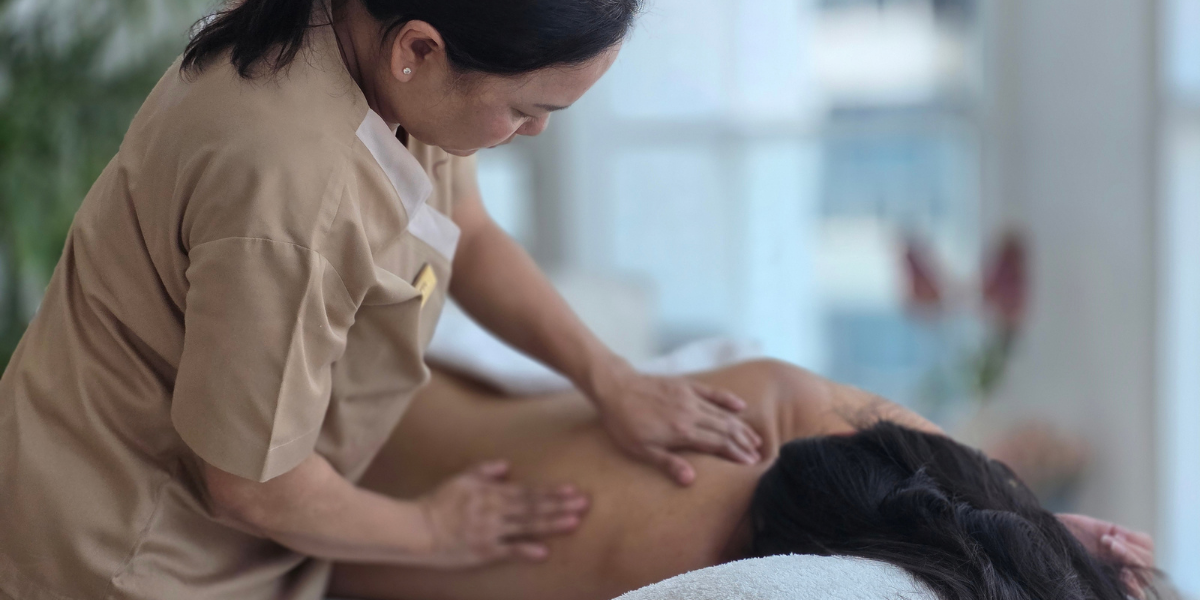 A massage therapist provides a back massage to a client in a serene setting