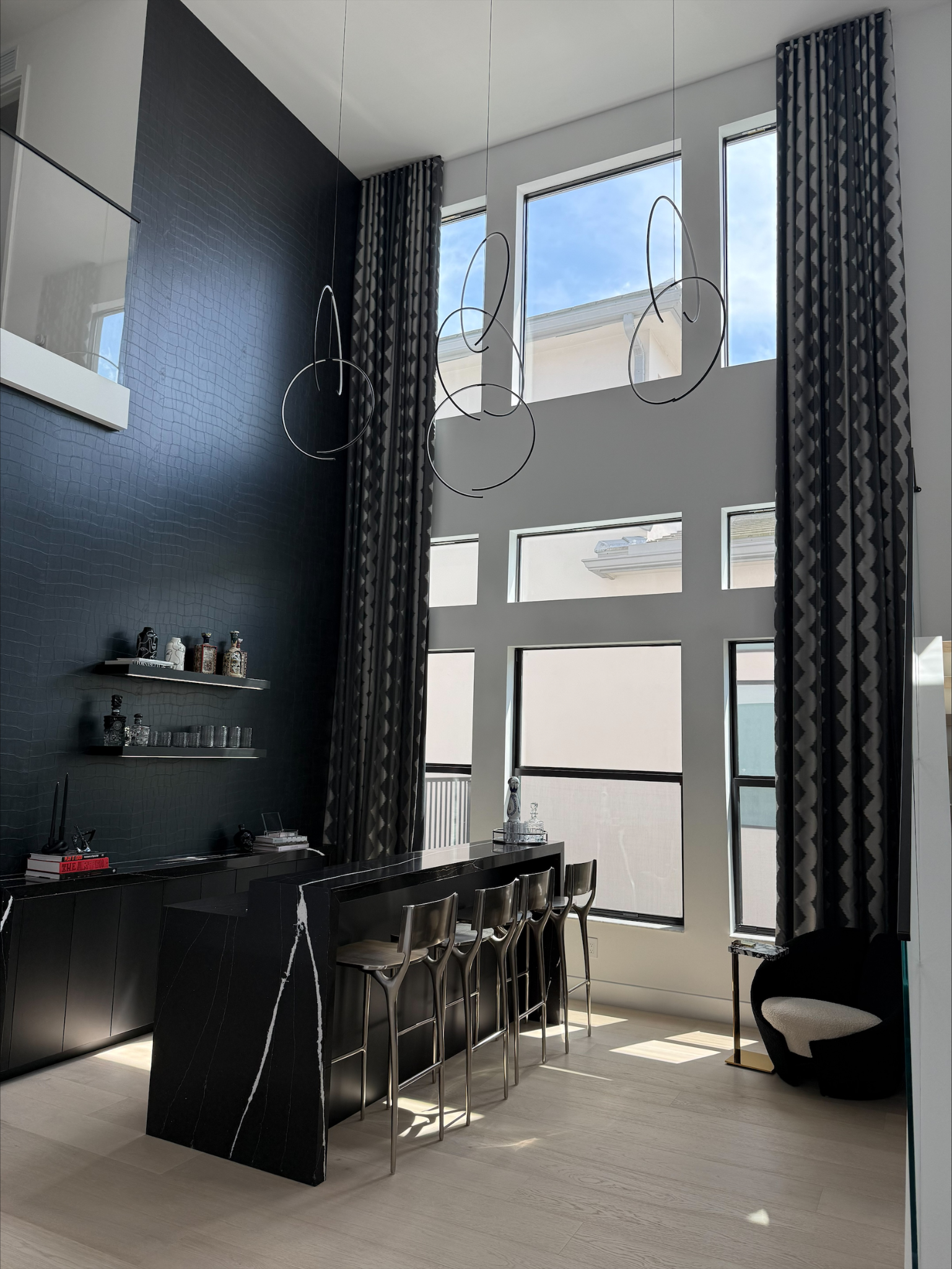 Modern kitchen with high ceilings, large windows, and stylish bar seating.