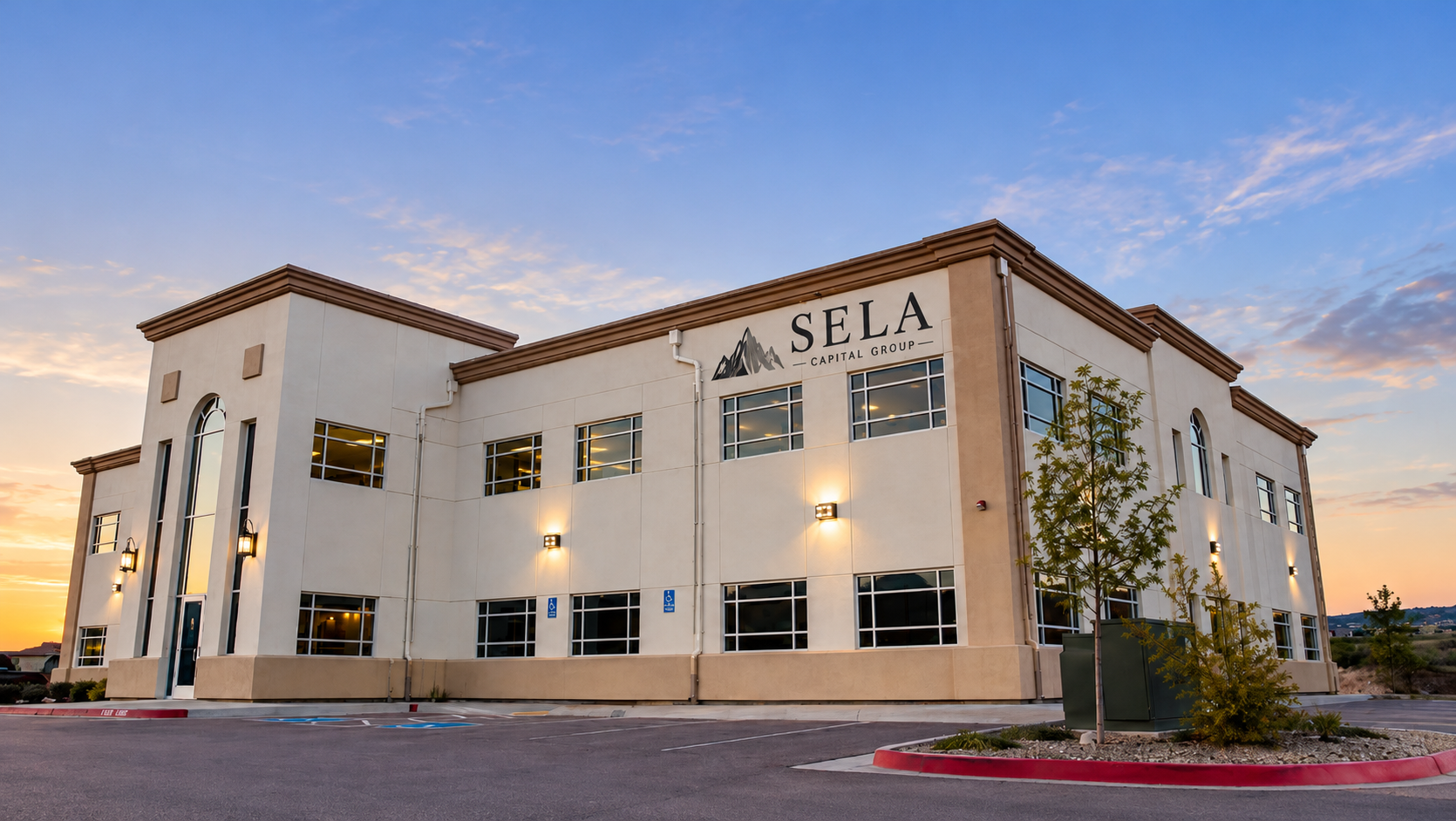 Modern office building with the sign "SELA Capital Group" against a sunset backdrop