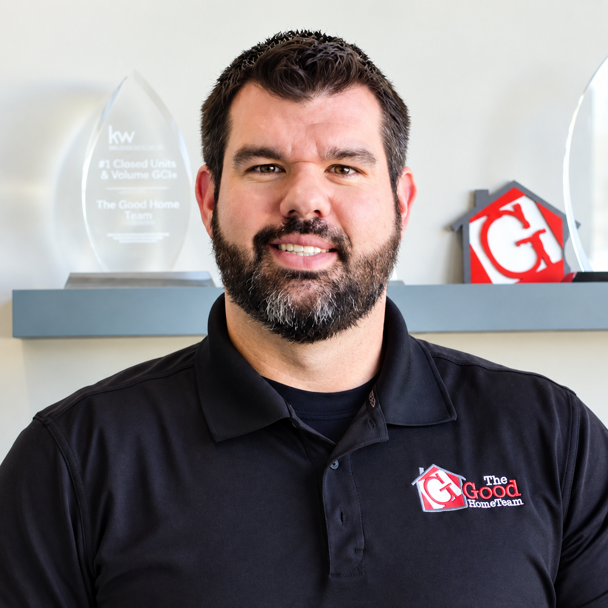 Man with a beard in a polo shirt standing in an office setting