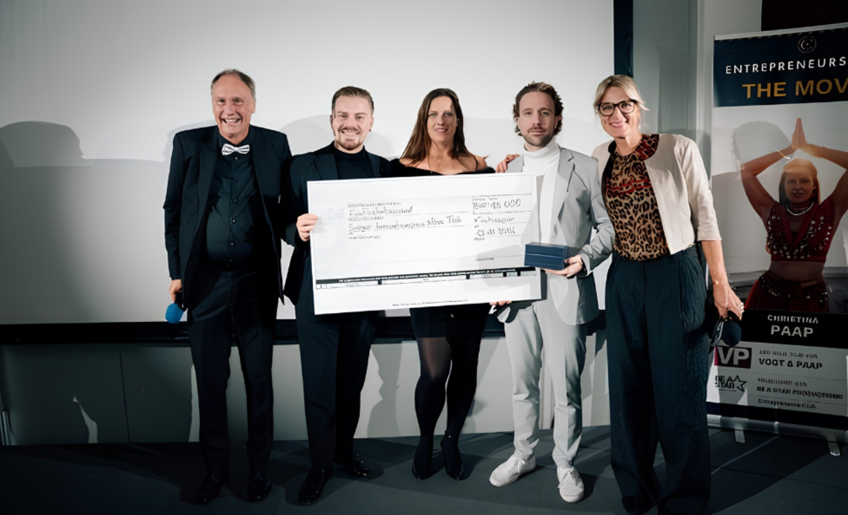 Five people holding a large check at an award ceremony event