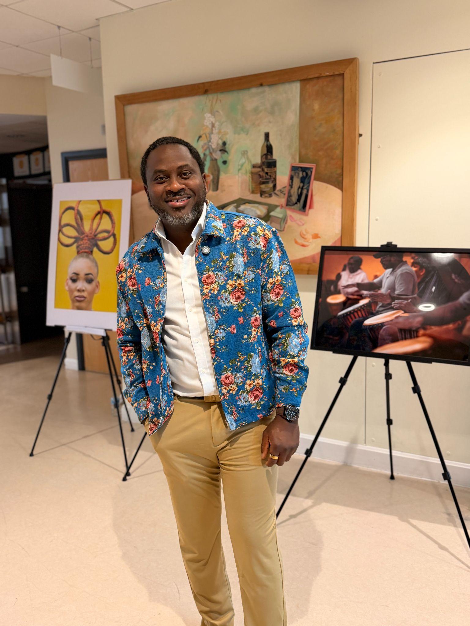 A man poses in a floral jacket in an art gallery setting