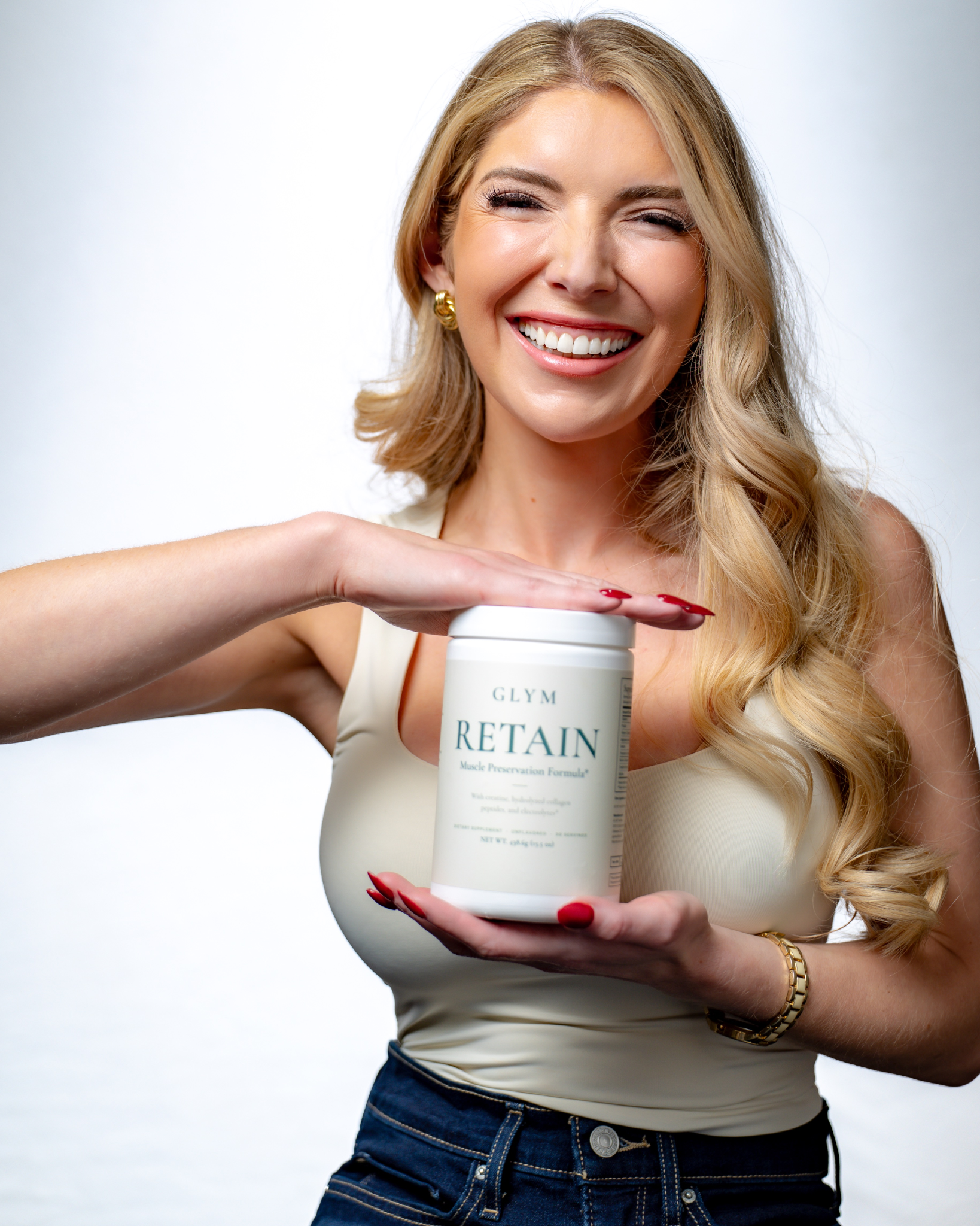 Smiling woman holding a container of Glym Retain hair product against a light background