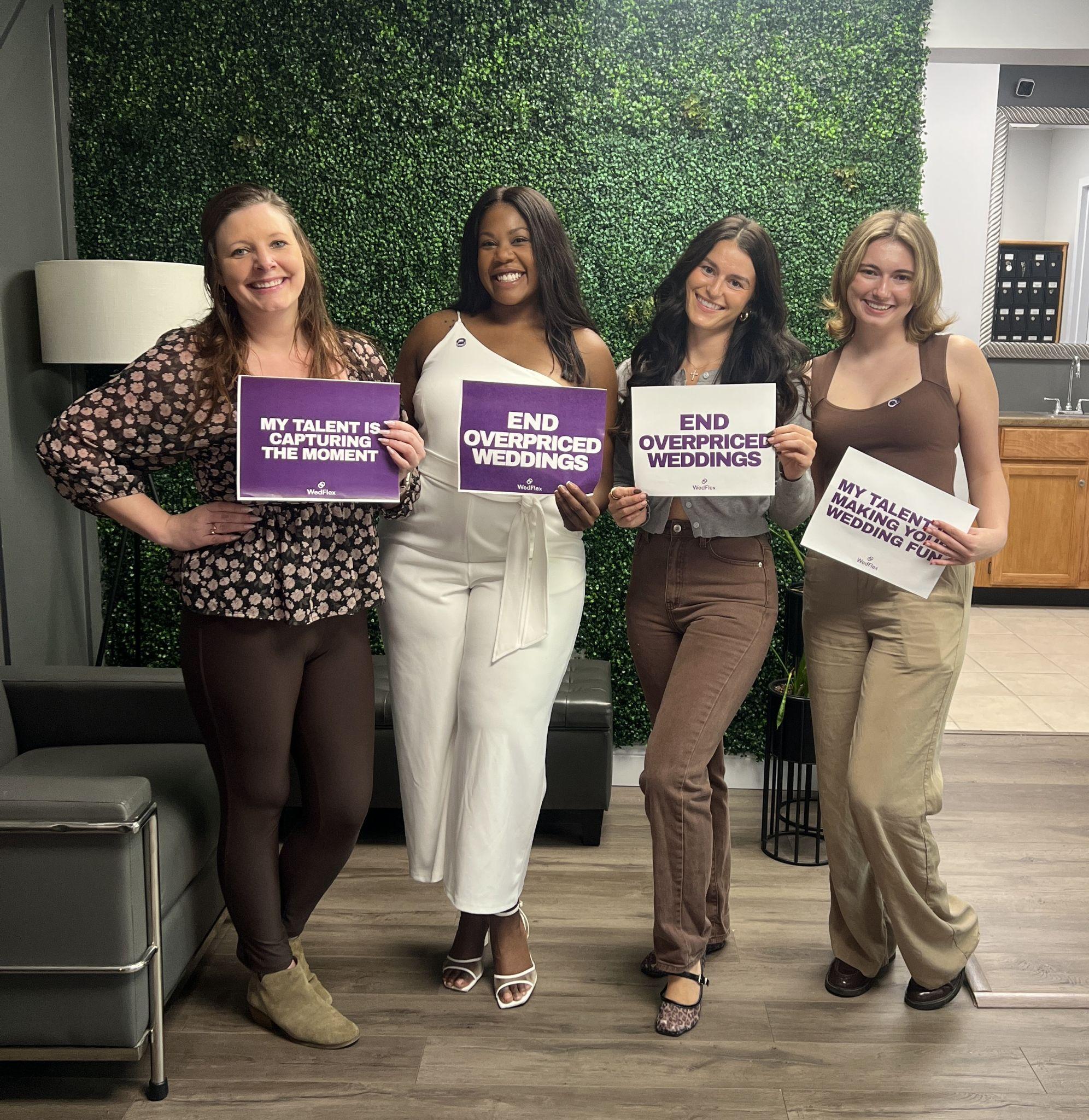 Four women hold signs promoting affordable weddings in a cozy indoor setting