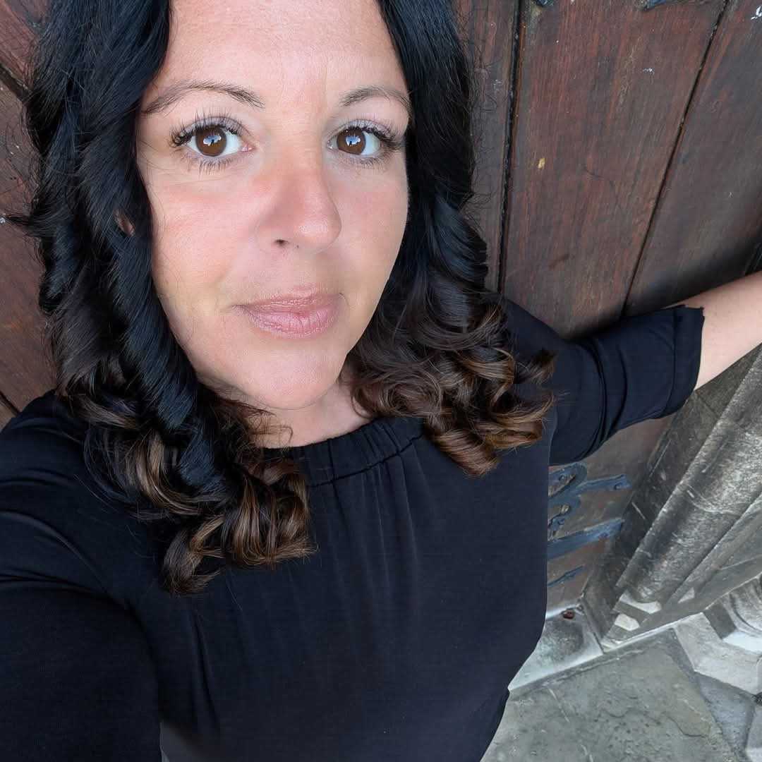 Woman with long black hair posing in front of a wooden door