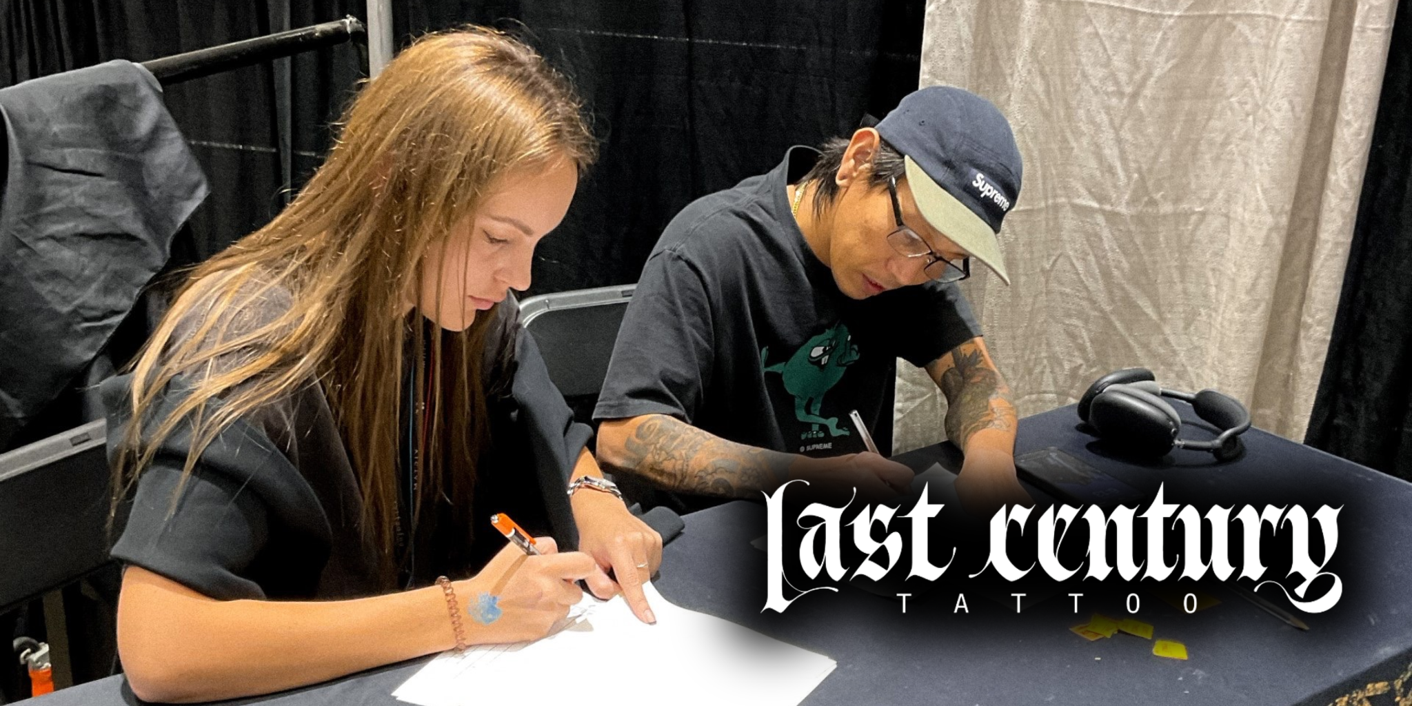 Tattoo artist sketching design with client at Last Century Tattoo studio.