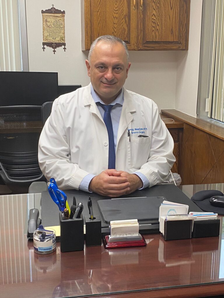 mutaf-behind-desk-lab-coat-siling-1-768x1024.jpeg